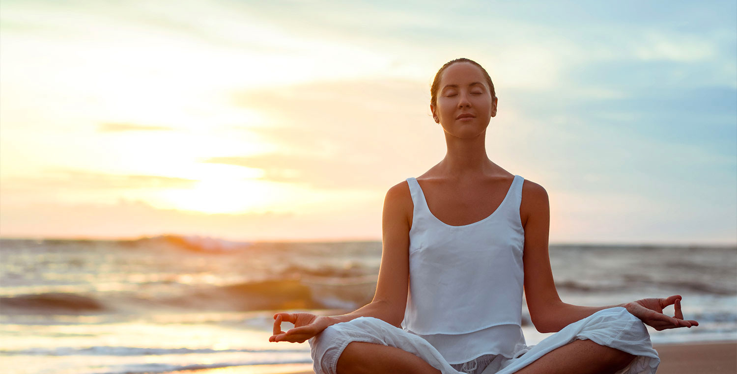 Woman meditating on beach